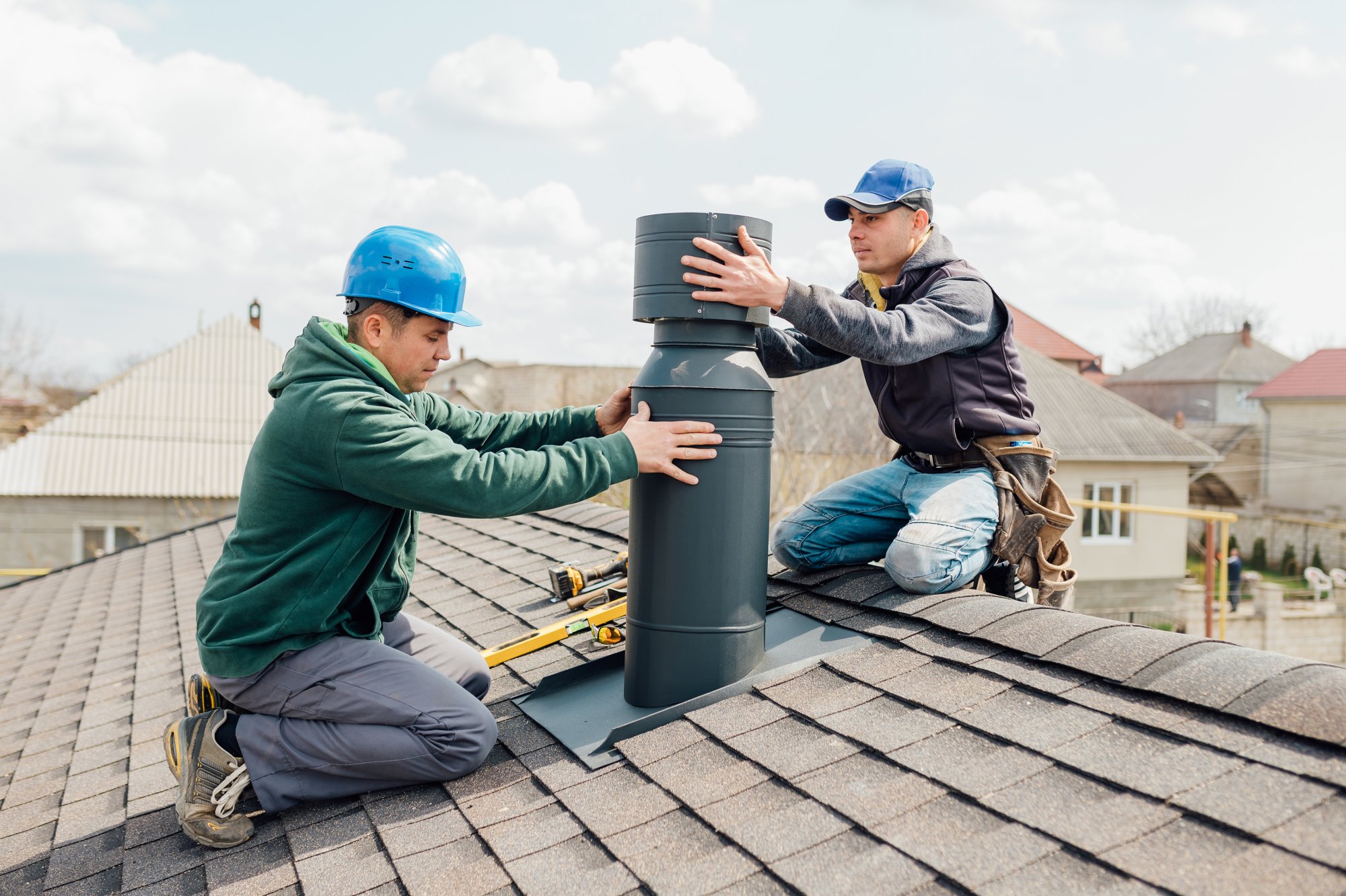 Two technicians installing a chimney liner pipe on a roof