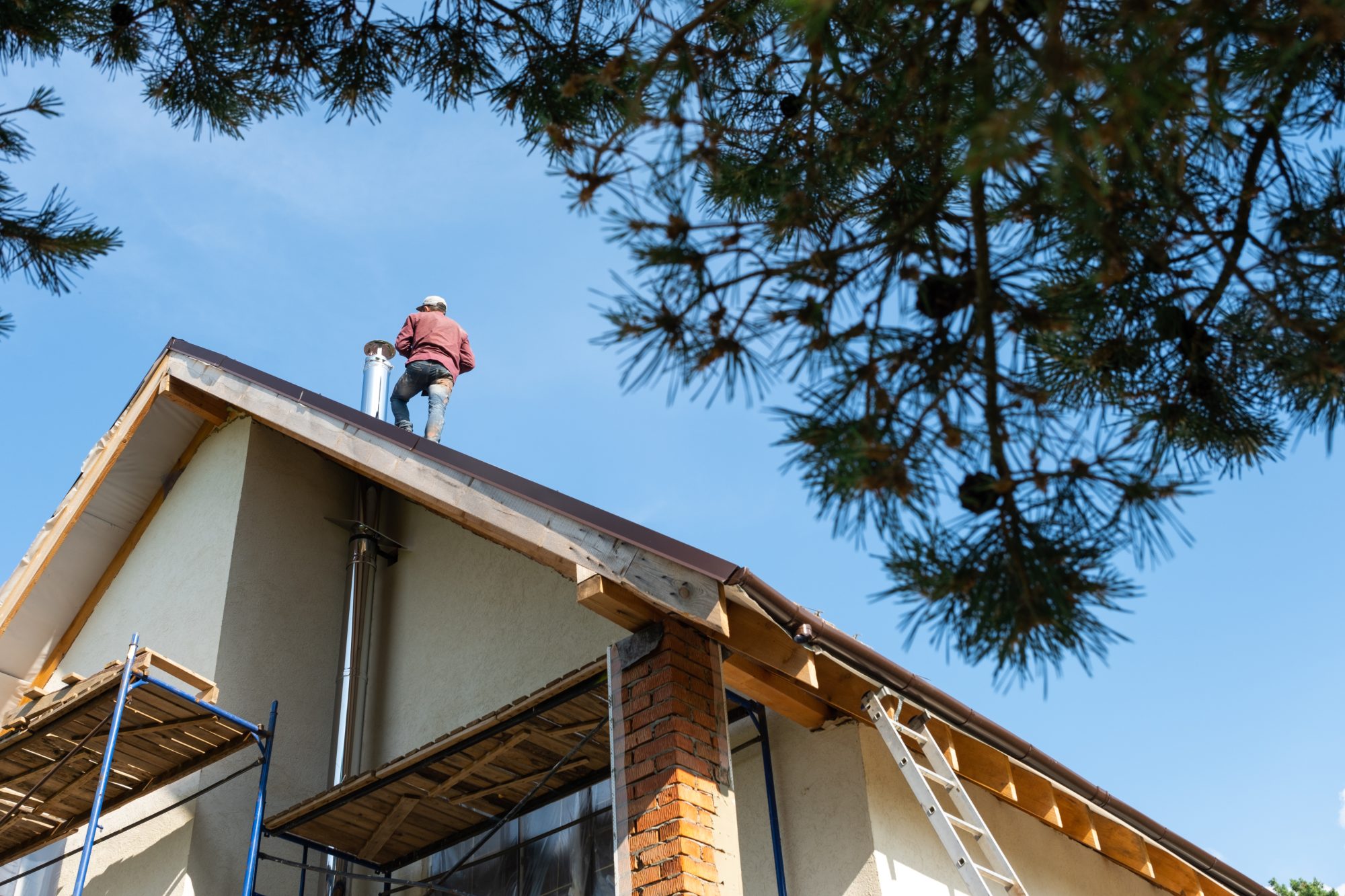 Technician standing on a roof beside a chimney during construction