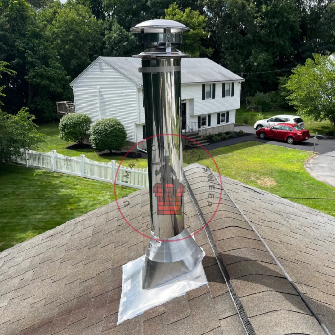 Technician installing a stainless steel chimney liner and cap on a residential roof